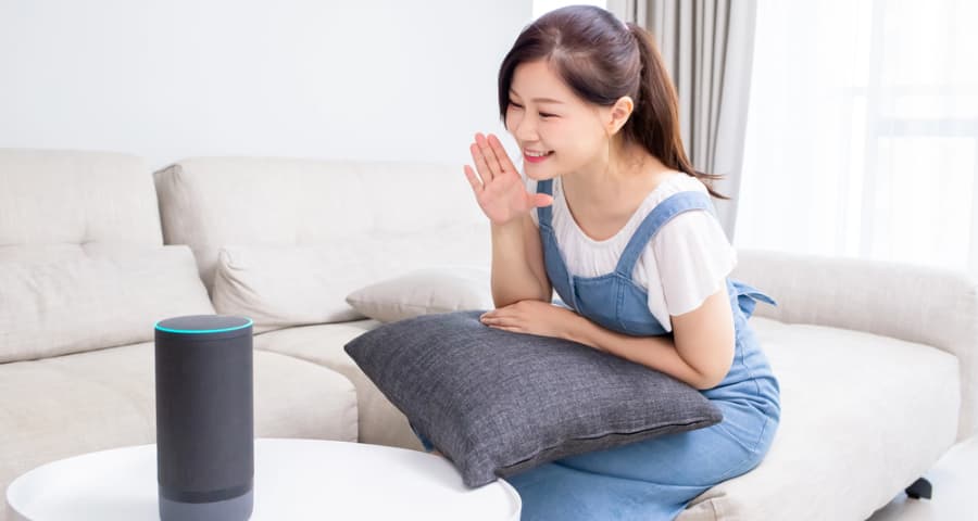 Young woman at home speaking a voice command to a smart speaker